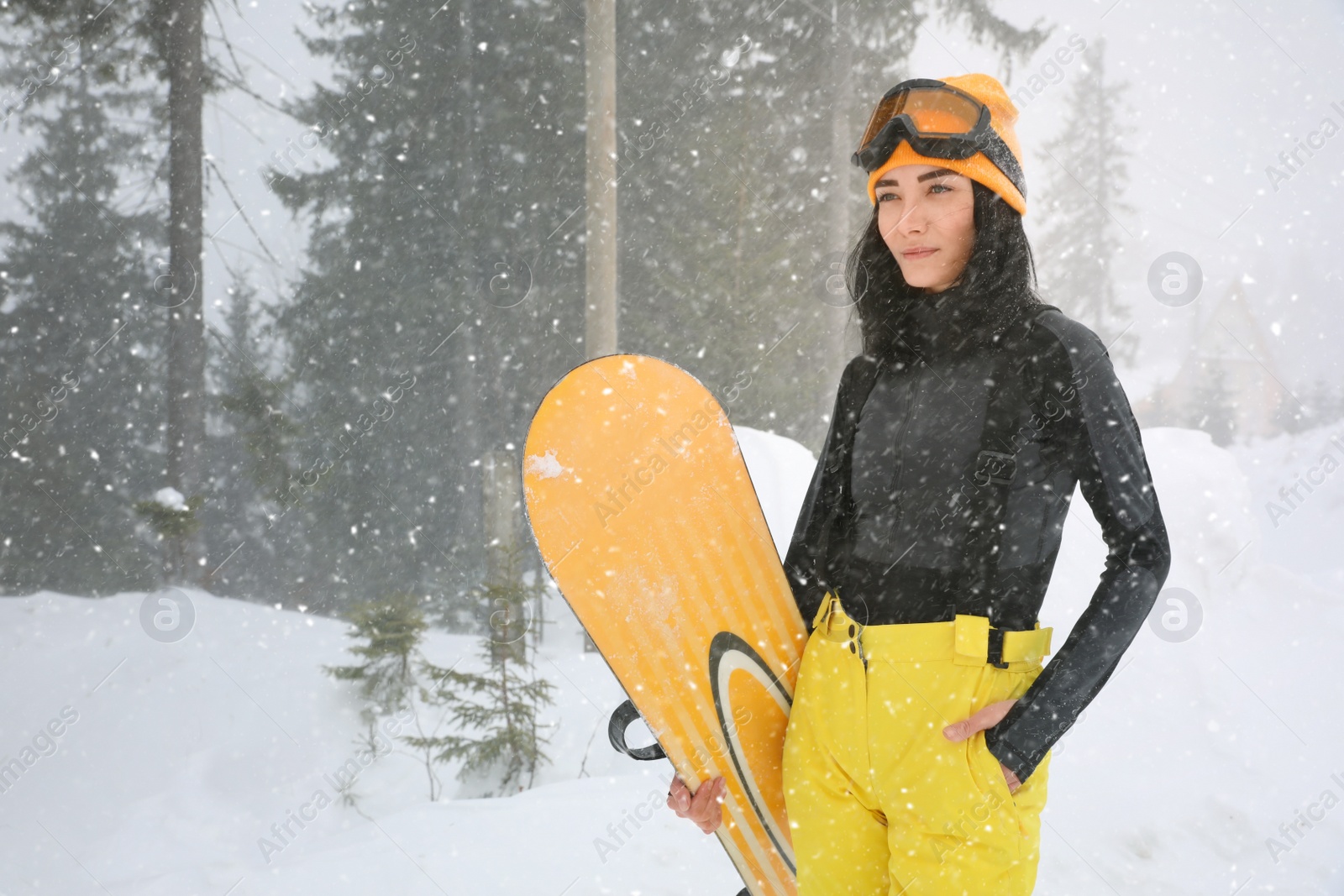 Photo of Young woman with snowboard wearing winter sport clothes outdoors