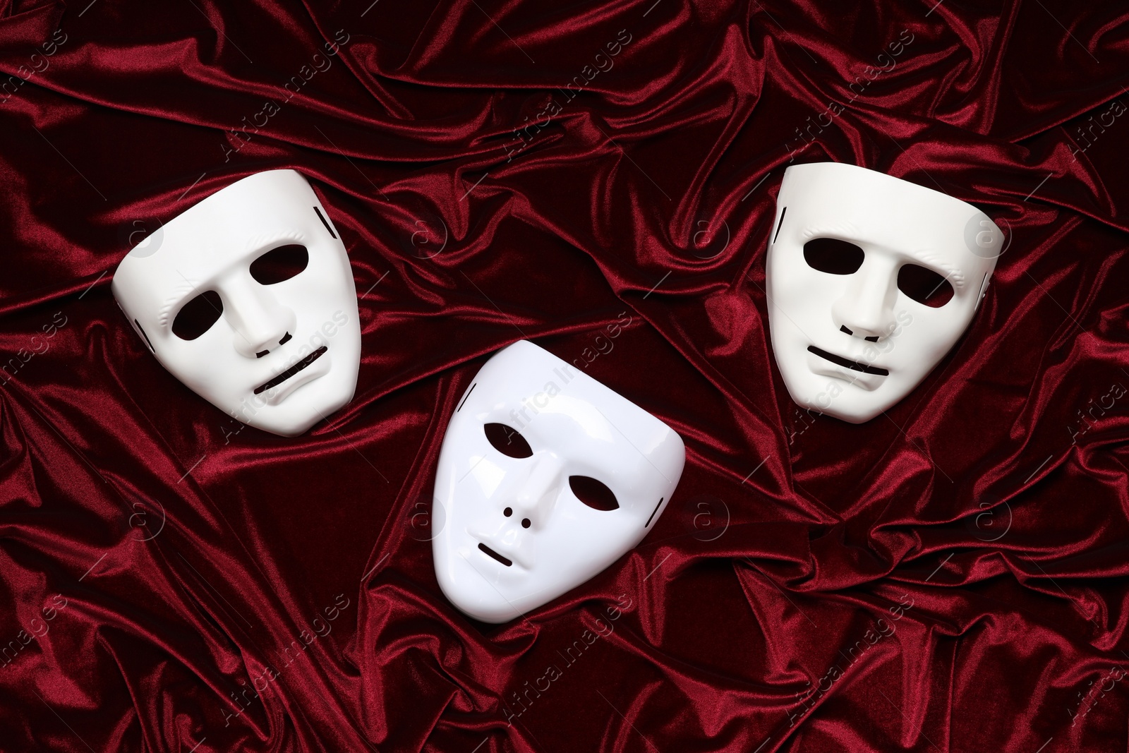 Photo of Theater arts. White masks on red fabric, top view