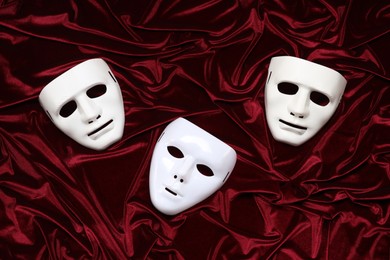 Theater arts. White masks on red fabric, top view