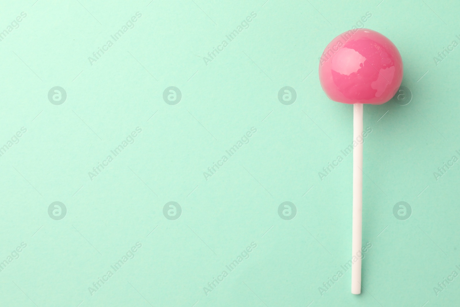 Photo of Tasty lollipop on turquoise background, top view. Space for text