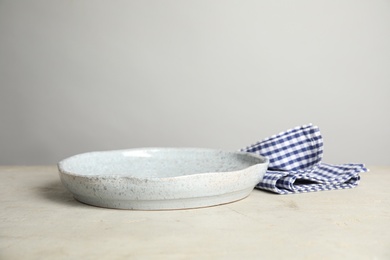 Photo of Empty plate and napkin on light table against grey background