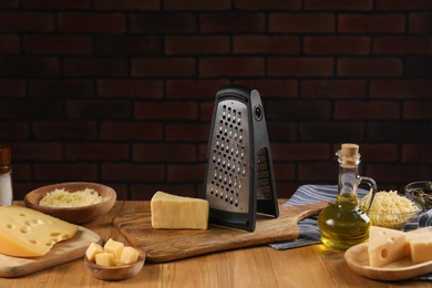 Different types of cheese and grater on wooden table