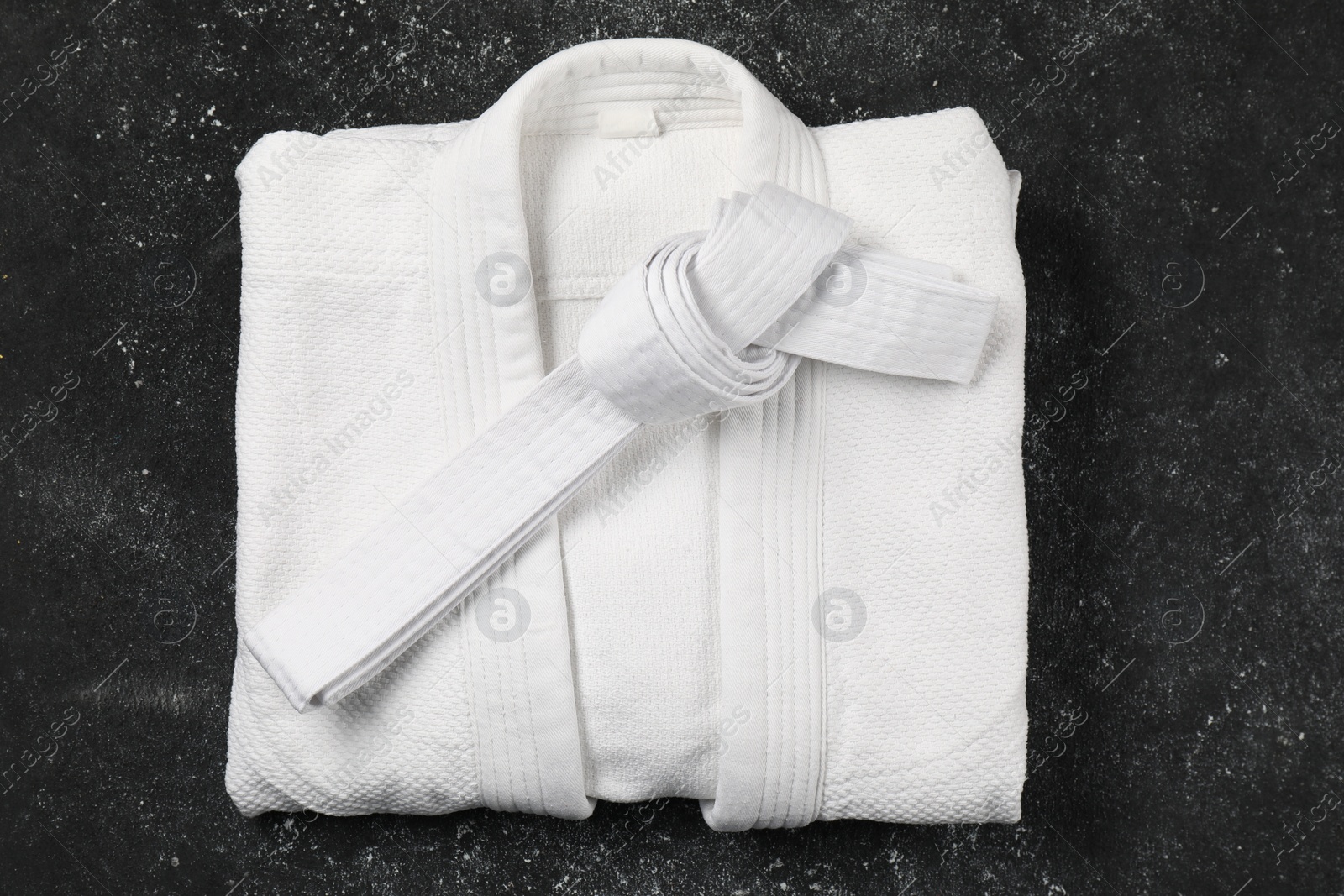 Photo of White karate belt and kimono on gray background, top view