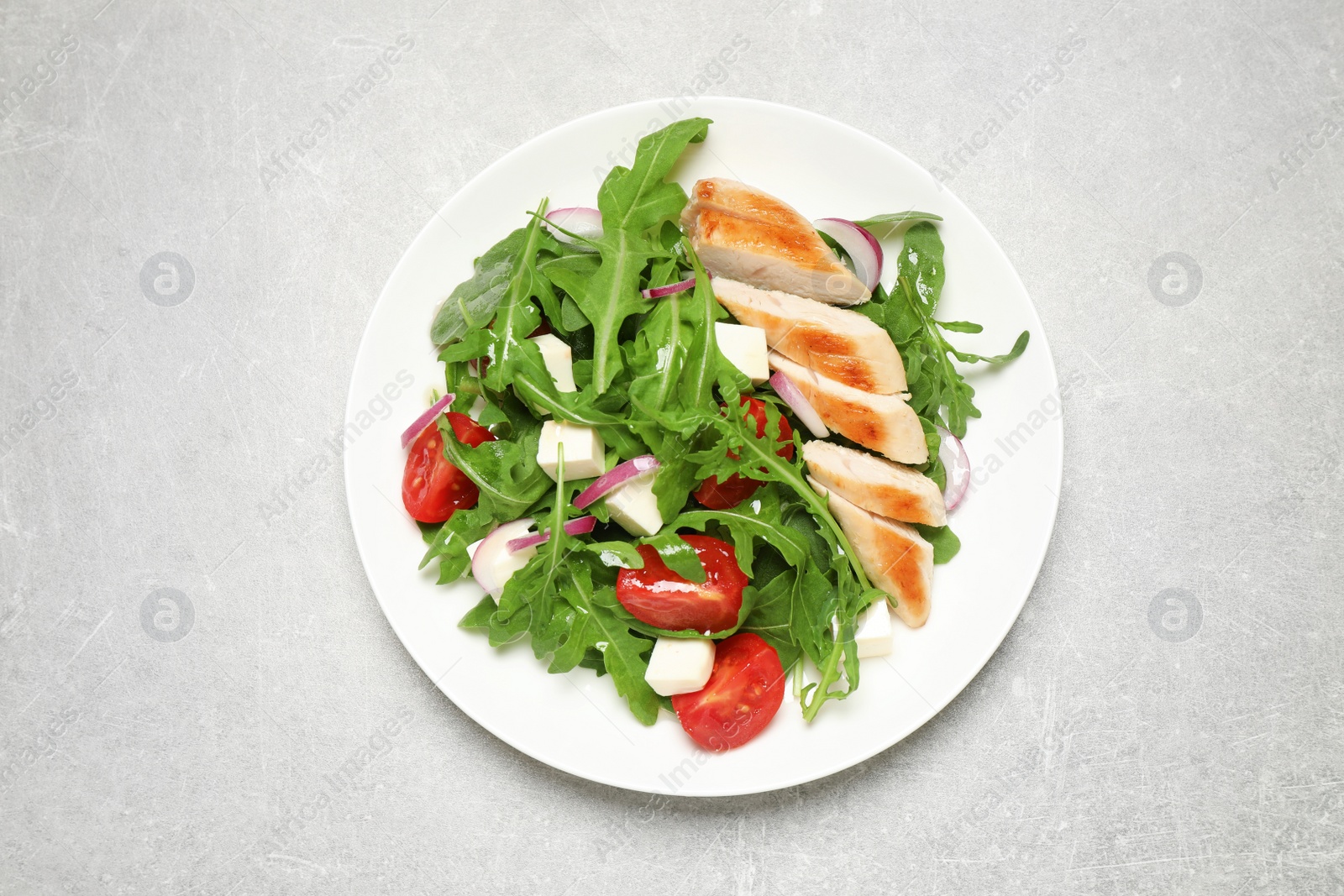 Photo of Delicious salad with meat, arugula and vegetables on grey table, top view