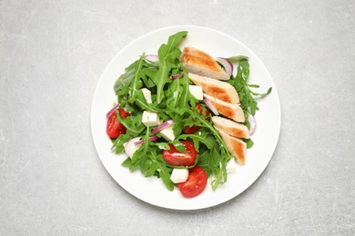 Photo of Delicious salad with meat, arugula and vegetables on grey table, top view