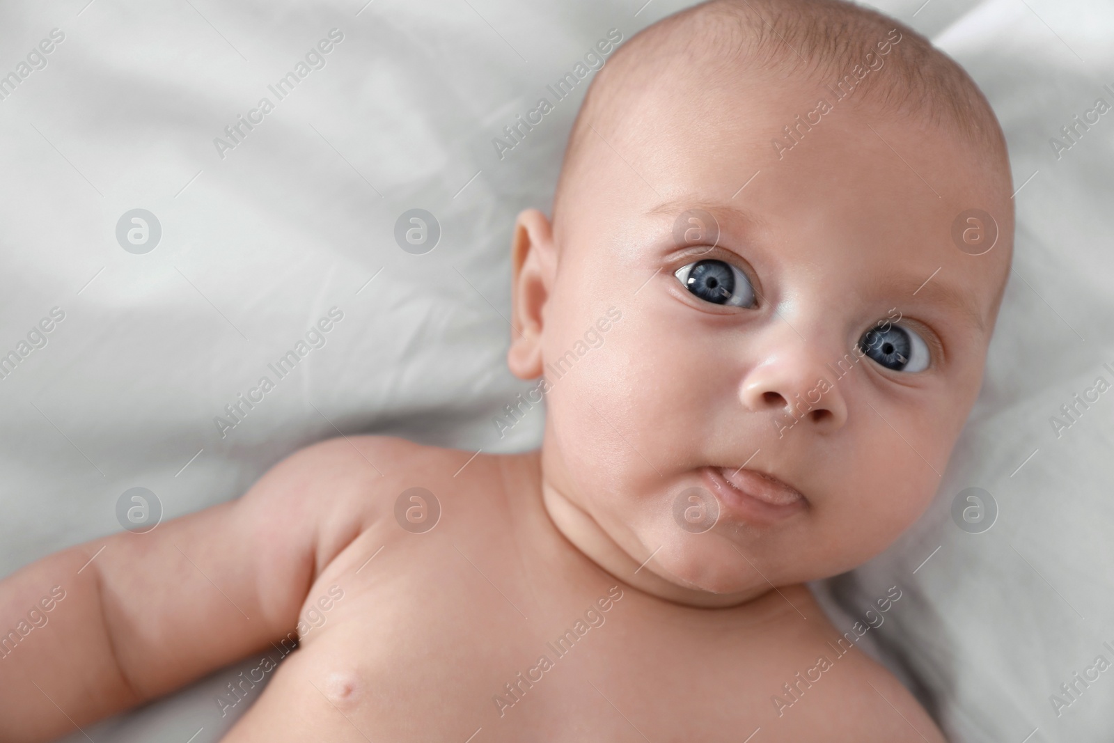 Photo of Cute little baby lying on bed, top view