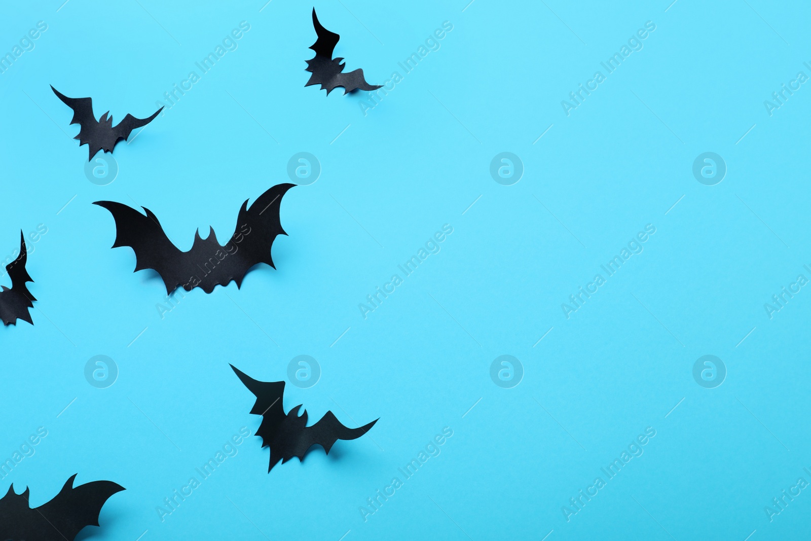 Photo of Paper bats on light blue background, flat lay with space for text. Halloween decor