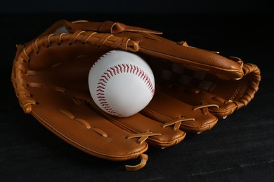 Photo of Catcher's mitt and baseball ball on black background. Sports game