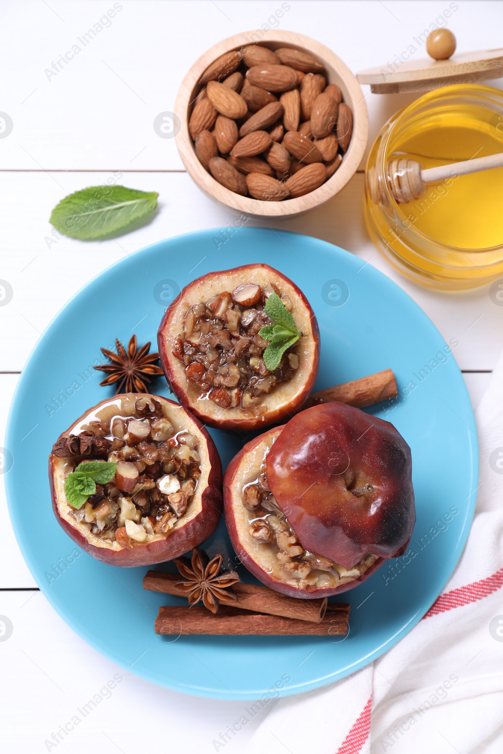 Photo of Tasty baked apples with nuts, honey, spices and mint on white wooden table, flat lay