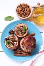 Tasty baked apples with nuts, honey, spices and mint on white wooden table, flat lay