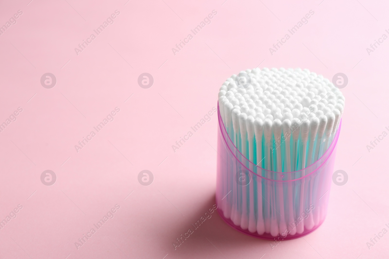 Photo of Plastic container with cotton swabs on color background. Space for text