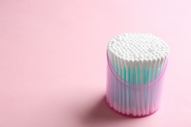 Plastic container with cotton swabs on color background. Space for text