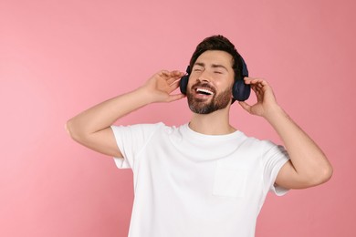 Photo of Happy man listening music with headphones on pink background