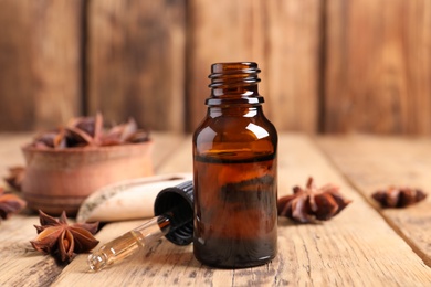 Photo of Bottle of essential oil, dropper and anise on wooden table