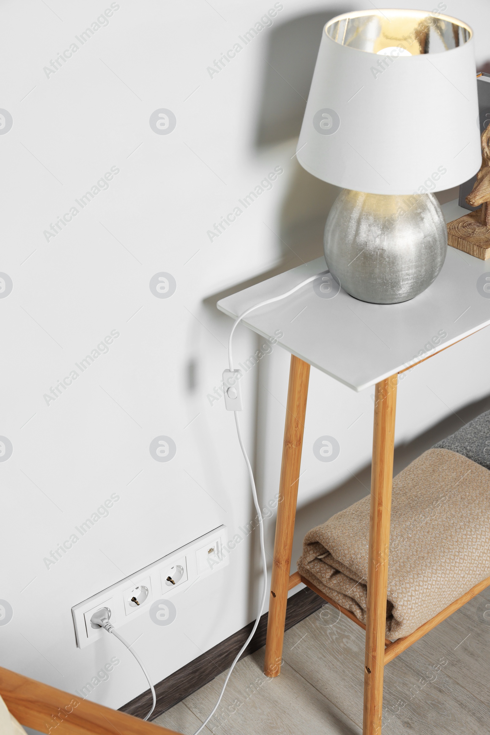 Photo of Electric power outlet sockets and plug on white wall indoors