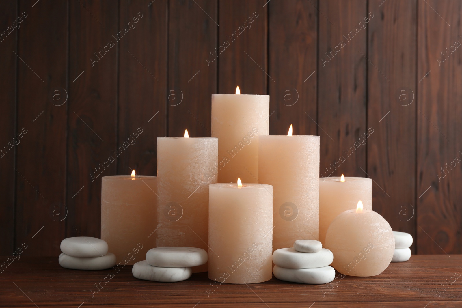 Photo of Composition with burning candles on table against wooden background