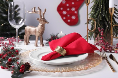 Photo of Plates with red fabric napkin, cutlery and festive decor on white table