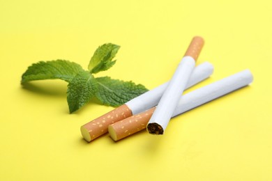 Photo of Menthol cigarettes and mint on yellow background