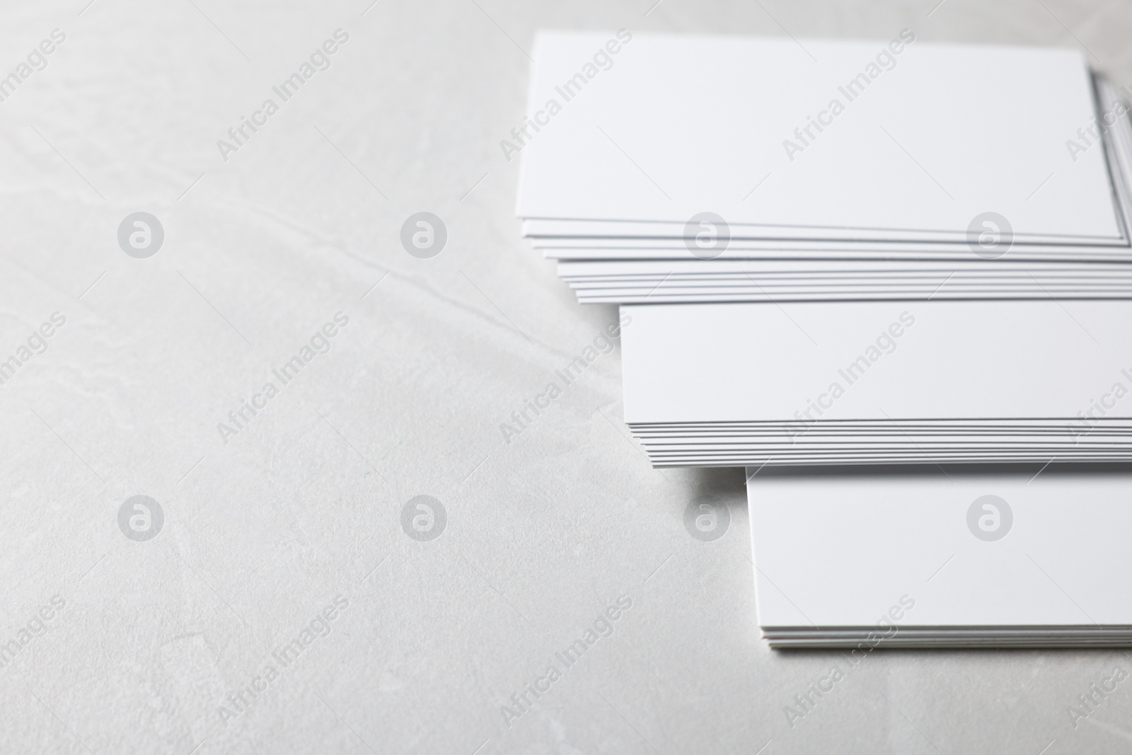 Photo of Blank business cards on light grey textured table, closeup. Mockup for design