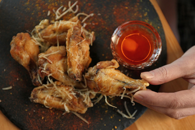 Photo of Woman eating tasty BBQ wings at table in cafe, closeup. Top view
