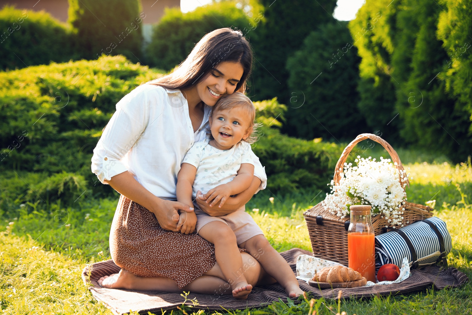 Photo of Mother with her baby daughter having picnic in garden on sunny day