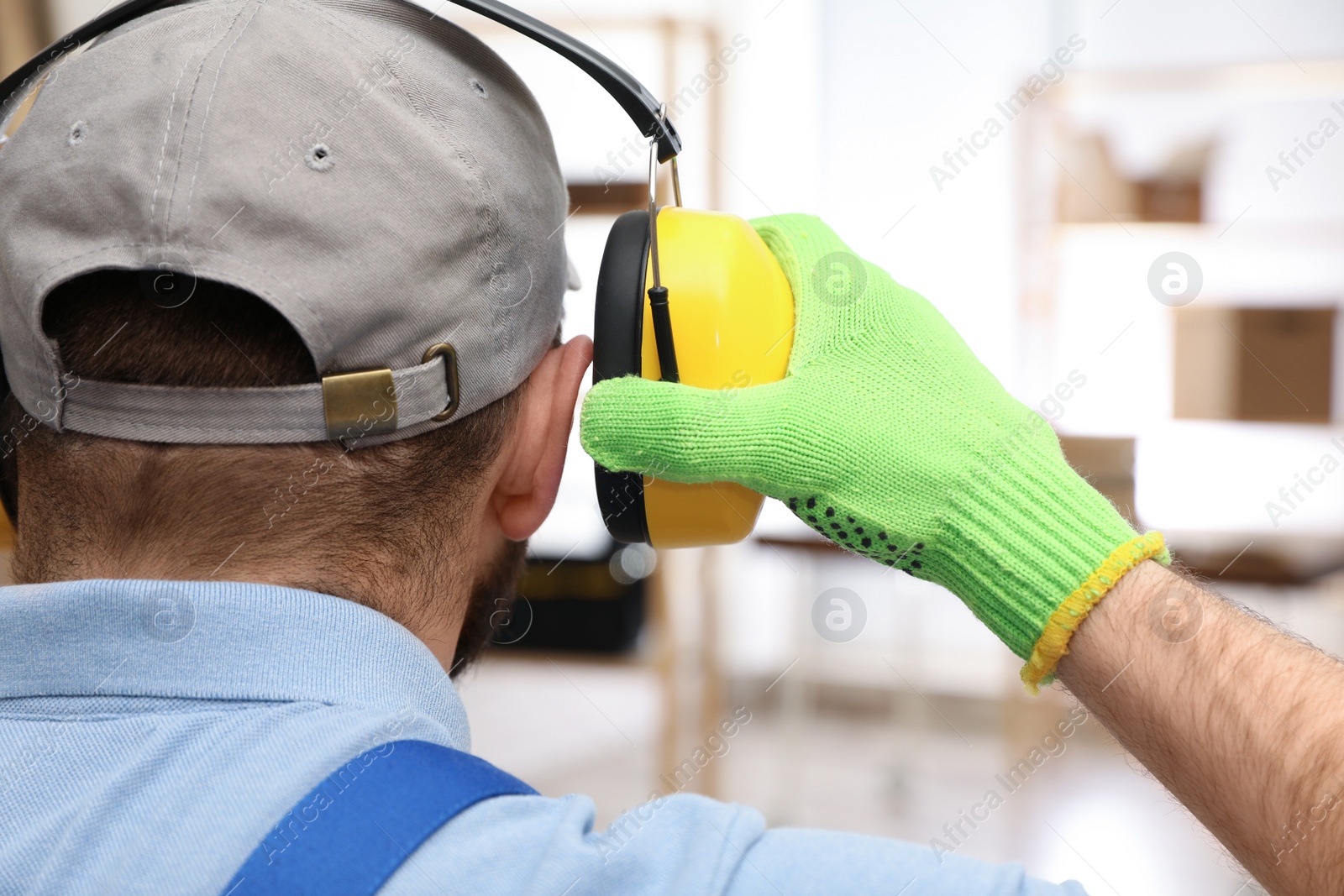 Photo of Worker wearing safety headphones indoors, back view. Hearing protection device