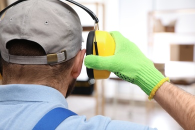 Photo of Worker wearing safety headphones indoors, back view. Hearing protection device