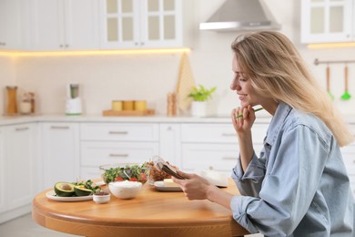 Photo of Woman with notebook and different products at wooden table in kitchen. Keto diet