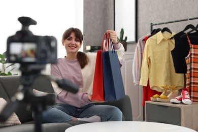 Photo of Smiling fashion blogger with shopping bags recording video at home