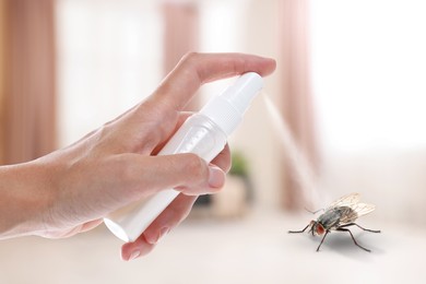 Image of Woman using fly spray in room, closeup