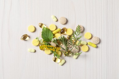 Photo of Different pills, herbs and flowers on white wooden table, flat lay. Dietary supplements