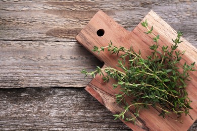 Photo of Board with aromatic fresh thyme on wooden table, top view. Space for text