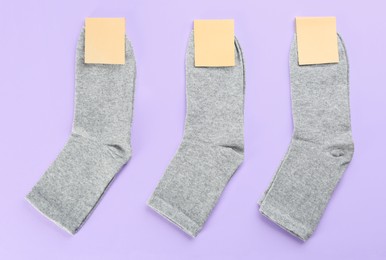 Photo of Soft cotton socks on lilac background, flat lay