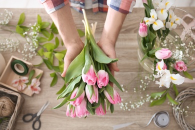 Photo of Male decorator creating beautiful bouquet at table, top view