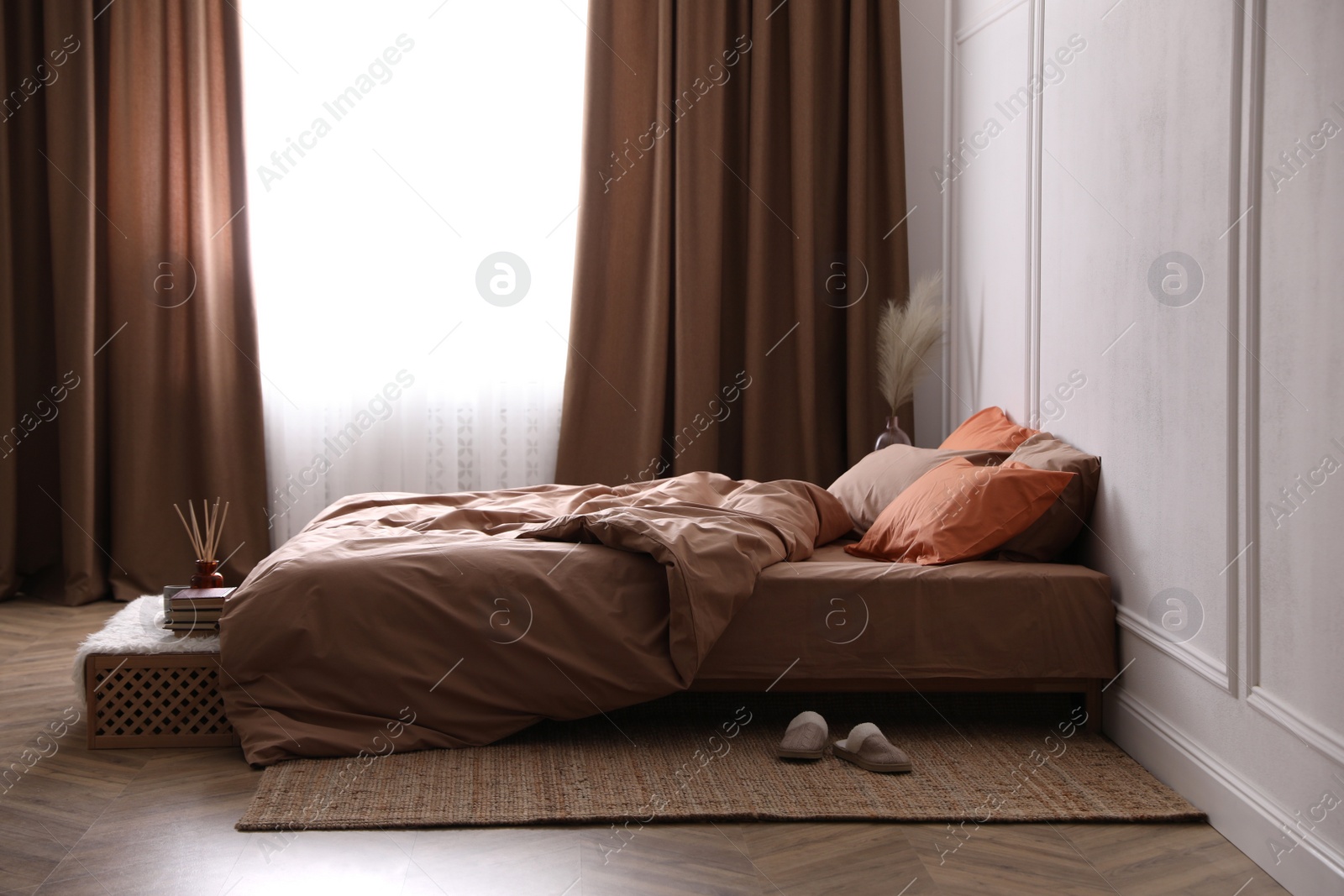 Photo of Bed with orange and brown linens in stylish room