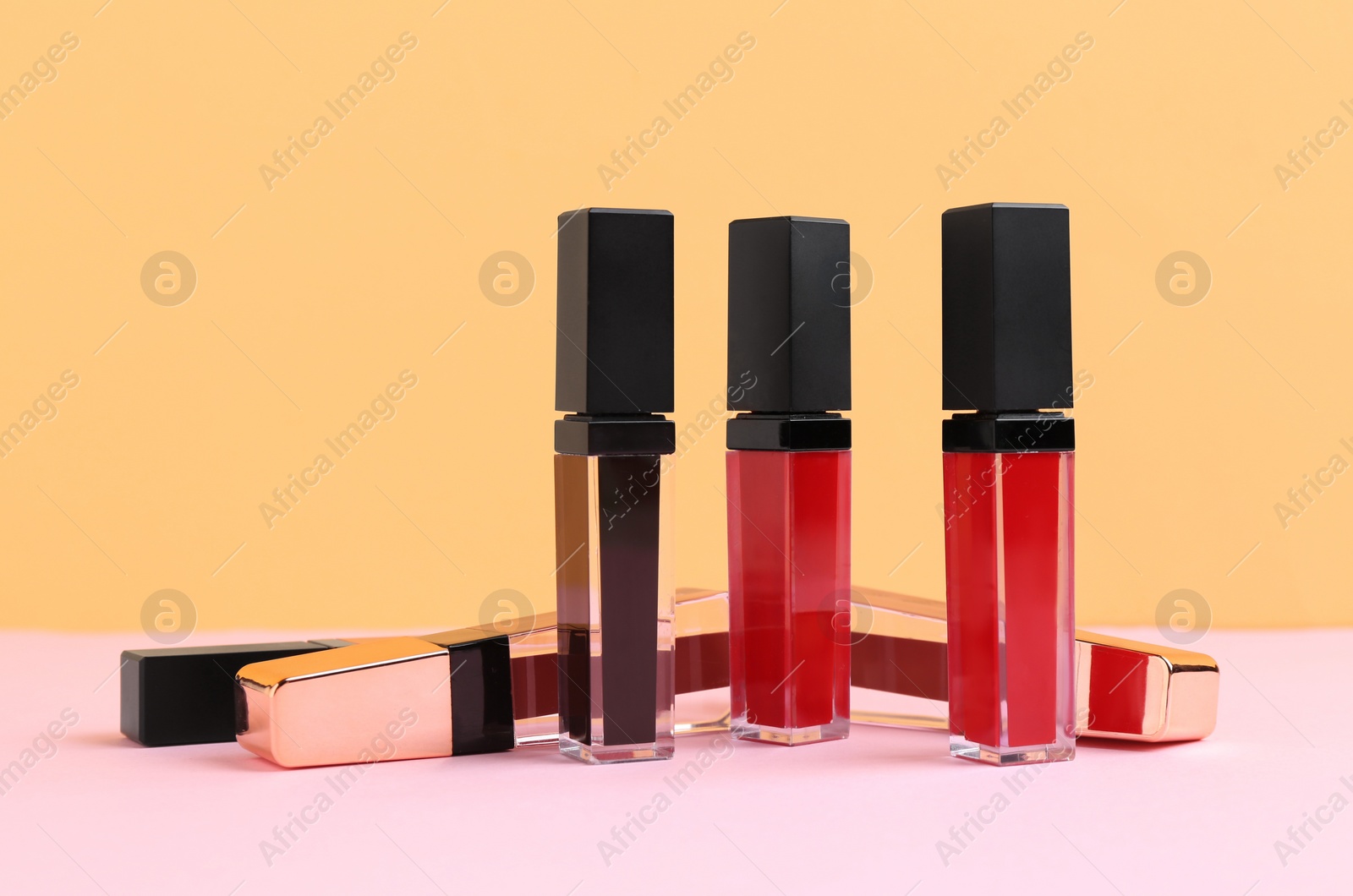 Photo of Many different lip glosses on color background