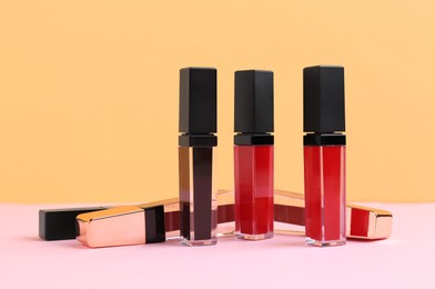 Photo of Many different lip glosses on color background