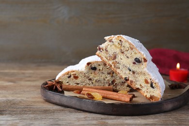 Photo of Plate of cut delicious Stollen sprinkled with powdered sugar and ingredients on wooden table