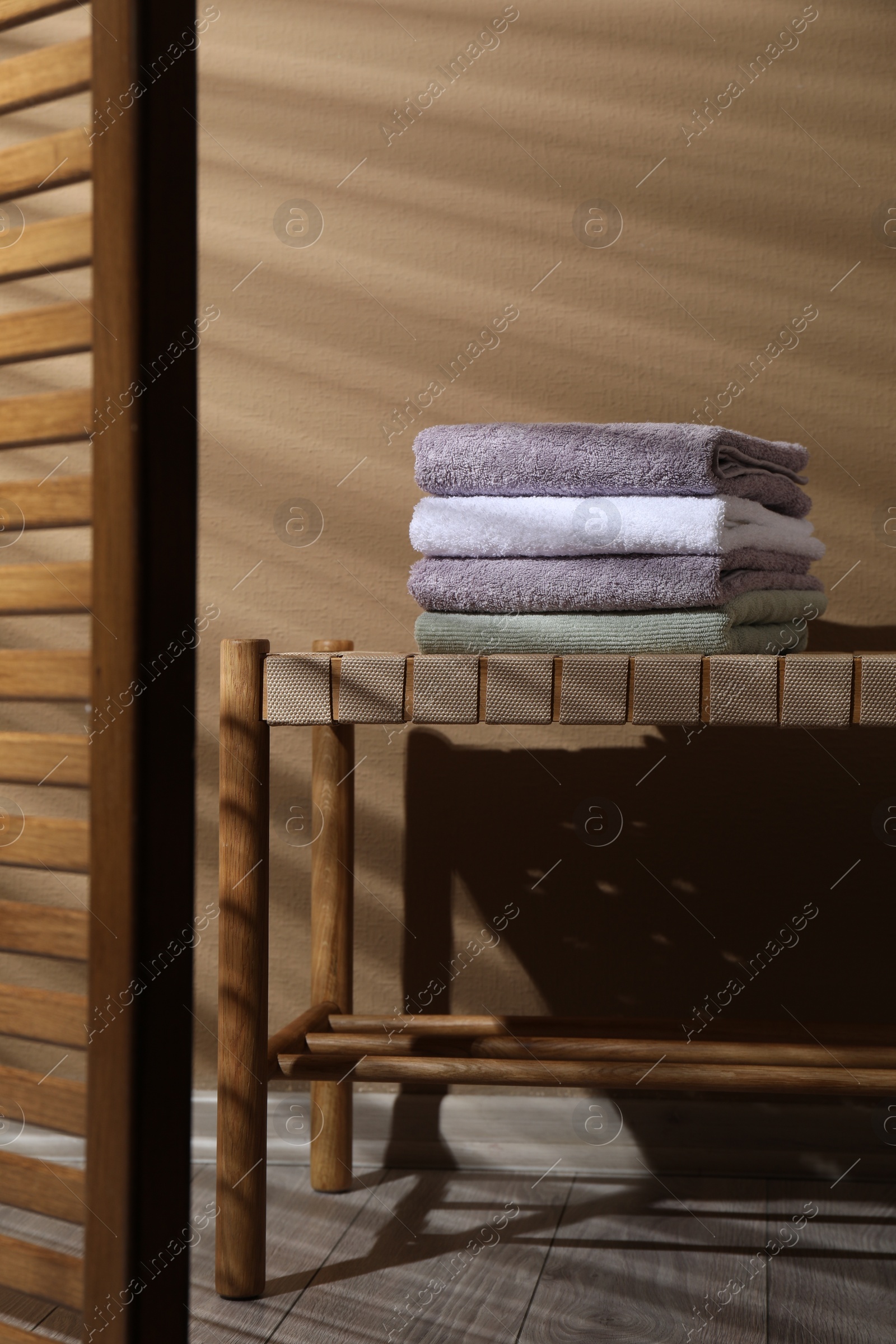 Photo of Stacked terry towels on wicker bench indoors