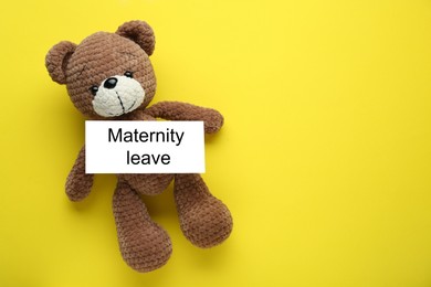 Photo of Toy bear and note with words Maternity Leave on yellow background, top view. Space for text