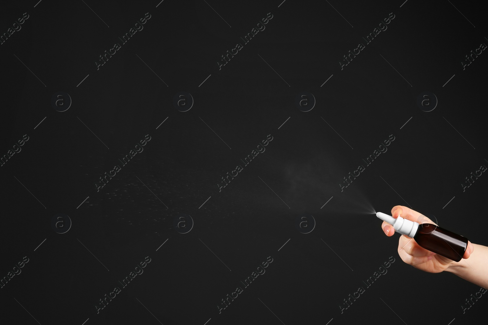 Photo of Nasal congestion. Woman spraying remedy from bottle on black background, closeup with space for text