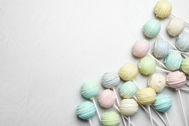 Photo of Sweet cake pops on light grey background, flat lay. Space for text