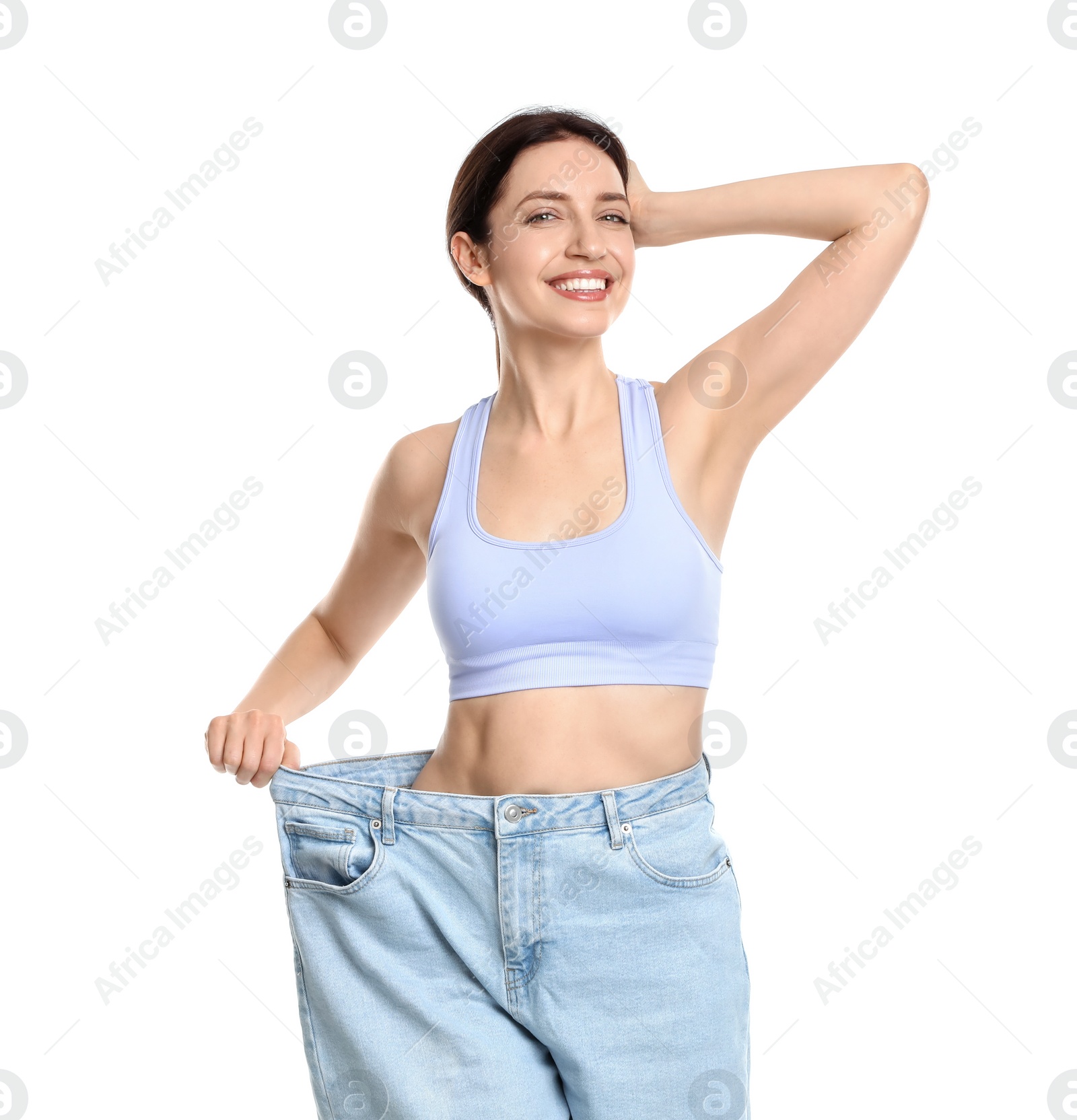 Photo of Happy young woman in big jeans showing her slim body on white background