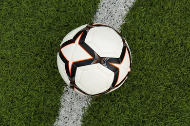 New soccer ball on green football field, top view