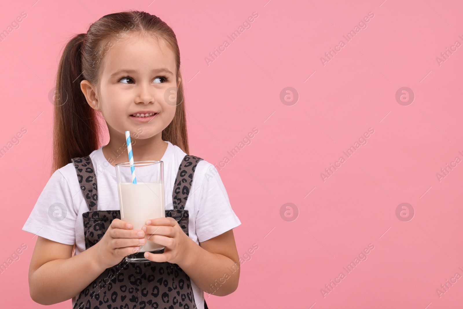 Photo of Cute girl with glass of fresh milk on pink background, space for text