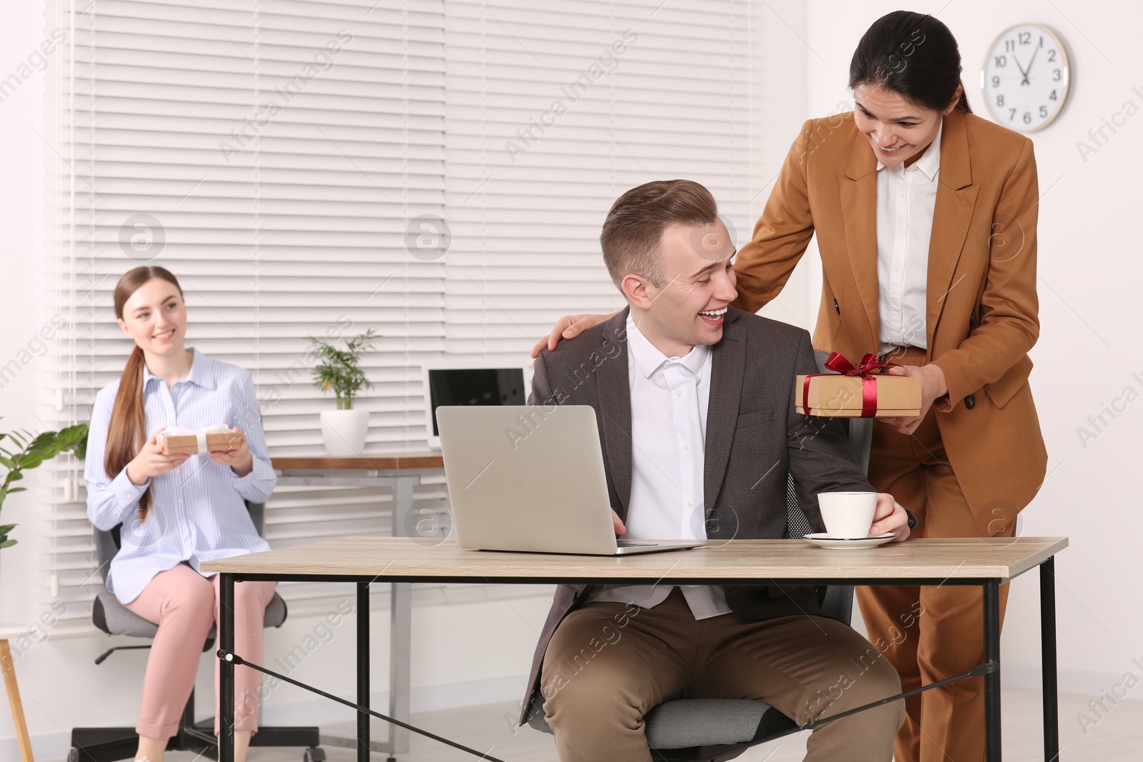 Photo of Woman presenting gift to her colleague in office