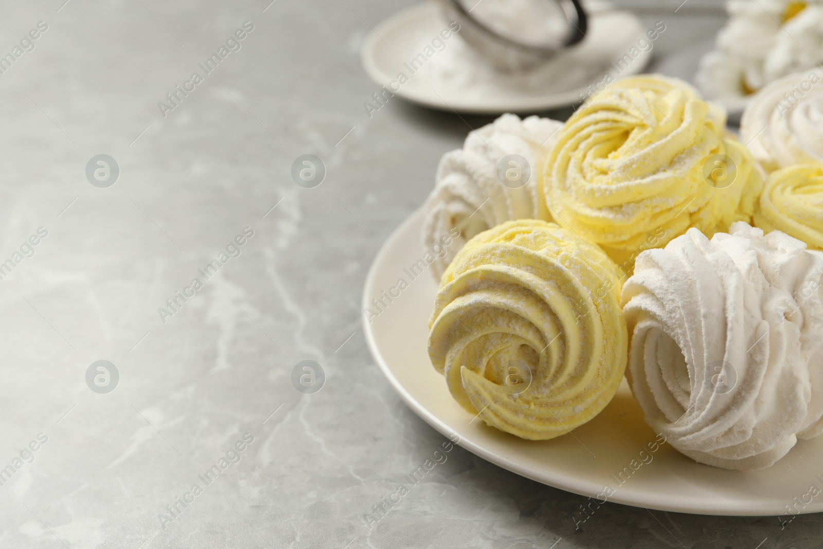 Photo of Delicious white and yellow marshmallows on grey marble table. Space for text