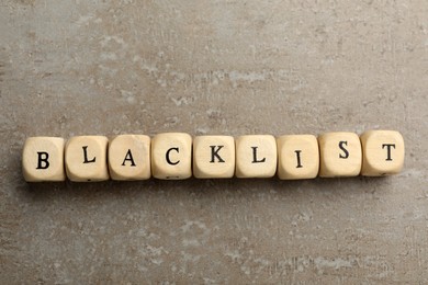 Photo of Wooden cubes with word Blacklist on grey background, flat lay