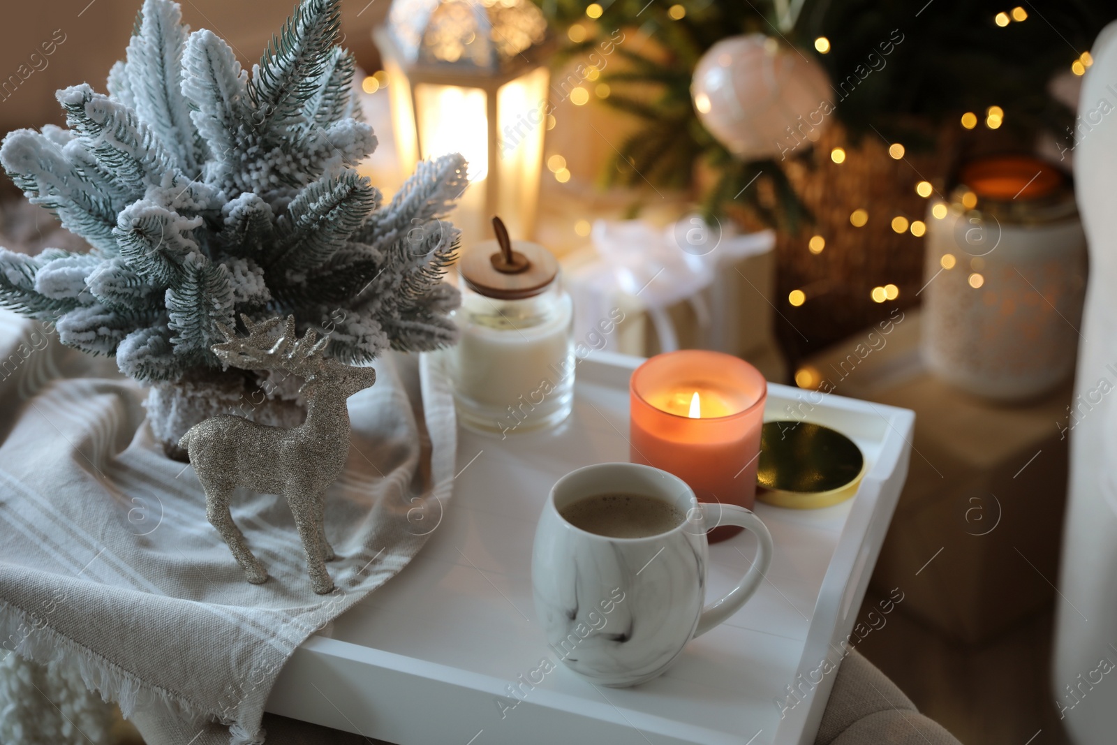 Photo of Cupcocoa, candle and decorative deer on tray at home. Christmas celebration