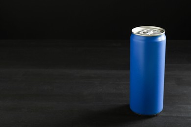 Photo of Energy drink in blue can on black wooden table, space for text